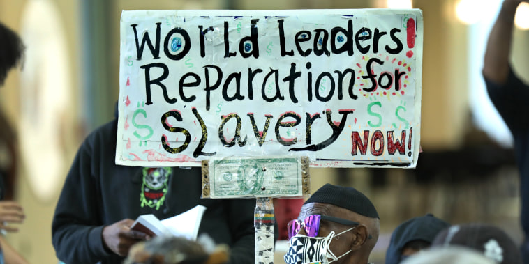 Walter Foster holds up a sign as the Reparations Task Force meets to hear public input on reparations in Los Angeles