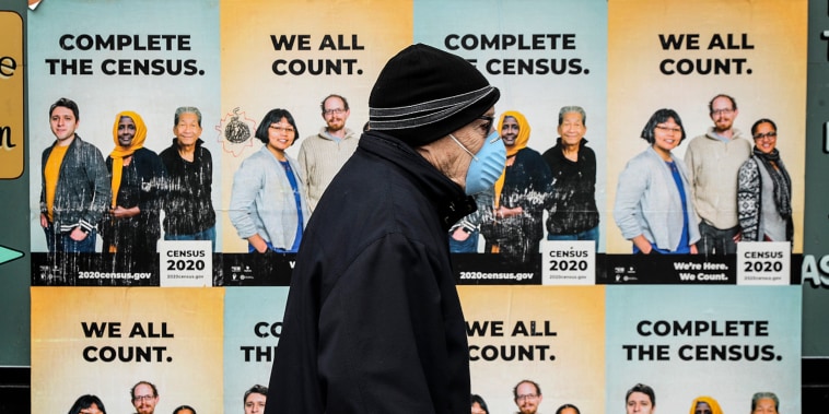 A man walks past posters encouraging participation in the 2020 Census in Seattle's Capitol Hill neighborhood on April 1, 2020.