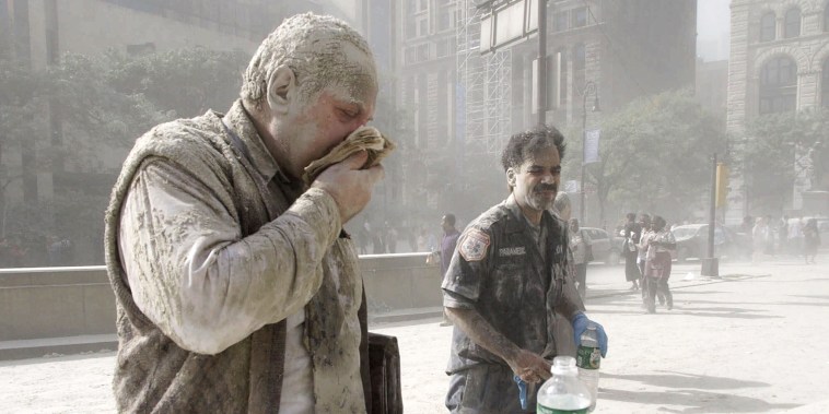 Carlos Nuñez, a paramedic, right, stands covered in dust after the collapse of the Twin Towers, in N.Y., on Sept. 11, 2001.