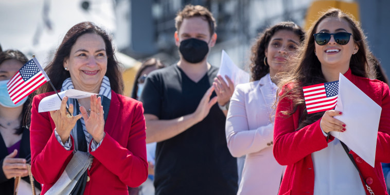 Maria Laura Limpias Chavez, left, of Bolivia, Sahara Loffsner, of Colombia, and fellow new American citizens, applaud after taking the Oath of Allegiance  during a naturalization ceremony on the flight deck of the USS Hornet Museum in Alameda, Calif., on Friday, July 2, 2021.