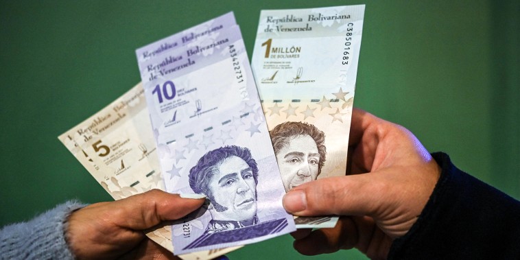 Image: People show the new five and ten bolivar bank notes put in circulation by the Central Bank of Venezuela as part of the currency reconversion, and another of one million bolivares that will continue to circulate with a value of one bolivar, after making a cash withdrawal at an ATM in Caracas on Oct. 1, 2021.
