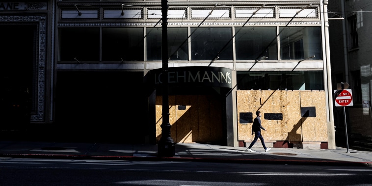 A pedestrian walks by a closed and boarded up business on April 16, 2021 in San Francisco.