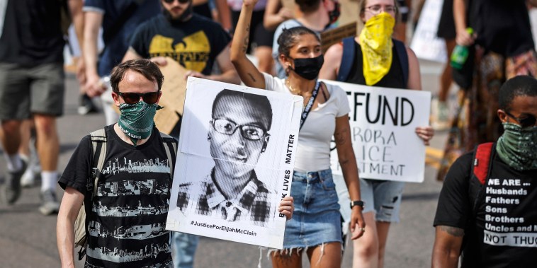 Demonstrators walk down Sable Boulevard during a rally and march over the death of Elijah McClain in Aurora, Colo., on June 27, 2020.