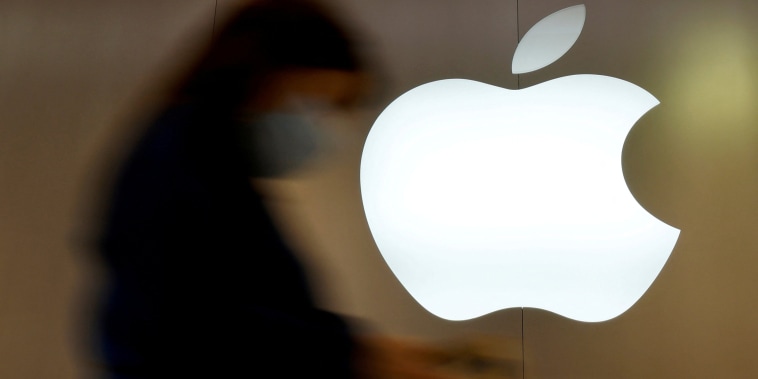 A woman walks past an Apple logo at an Apple store.