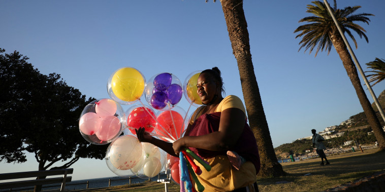 Image: Vendor Thando Ncube carries balloons at Camps Bay beach in Cape Town
