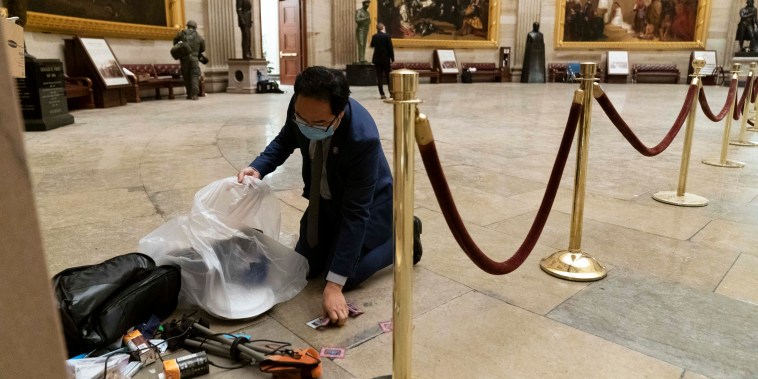 Rep. Andy Kim, D-N.J., cleans up debris and personal belongings strewn across the floor of the Rotunda in the early morning hours of Jan. 7, 2021, after protesters stormed the Capitol in Washington.