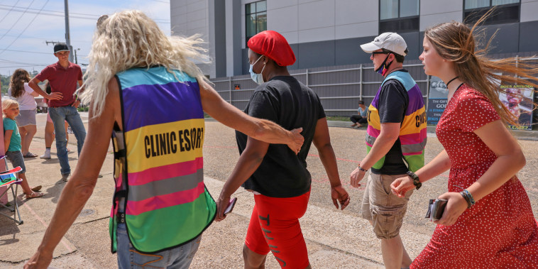 A clinic escort leads a woman surrounded by anti-abortion protesters at the Jackson Women's Health Organization in Jackson, Miss.