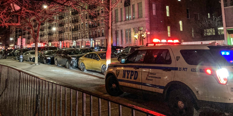 Police secure the scene outside a six story residential building, left, where two NYPD officers where shot responding to a domestic disturbance call in Harlem, Friday Jan. 21, 2022, in New York.