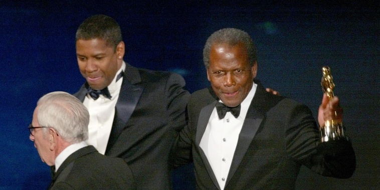 Image: Sidney Poitier walks off the stage with presenter Denzel Washington  after receiving an honorary Oscar during the 74th Academy Awards in Hollywood on March 24, 2002.