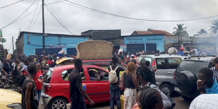 Image: People walk amid traffic near the site where a high-tension power cable snapped and fell on houses and a market on the outskirts of Kinshasa,  the Democratic Republic of the Congo, on Feb. 2, 2022.