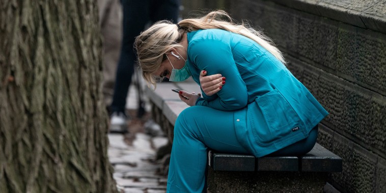 Image: A healthcare worker sits on a bench near Central Park in New York City on March 30, 2020.
