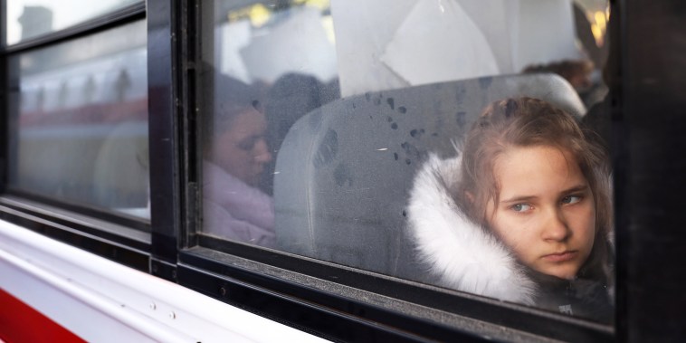 Ukrainians who are seeking asylum sit on a bus