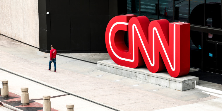 People walk by the world headquarters for CNN on March 15, 2022, in Atlanta.