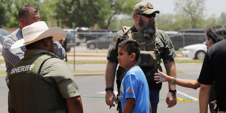 Un niño sube a un autobús escolar mientras el personal de las fuerzas del orden vigila la escena de un tiroteo en la Escuela Primaria Robb en Uvalde, Texas, Estados Unidos 24 de mayo de 2022.