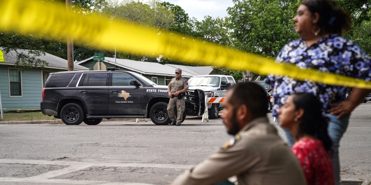 Image: People sit on the curb outside of Robb Elementary School as State troopers guard the area in Uvalde, Texas, on May 24, 2022.