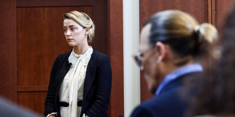 Amber Heard testifies as Johnny Depp looks on during a defamation trial at the Fairfax County Circuit Courthouse in Fairfax, Va., on May 5, 2022.