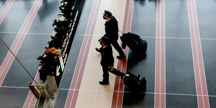 Airline pilots walk through Ronald Reagan Washington National Airport on Dec. 27, 2021, in Arlington, Va.