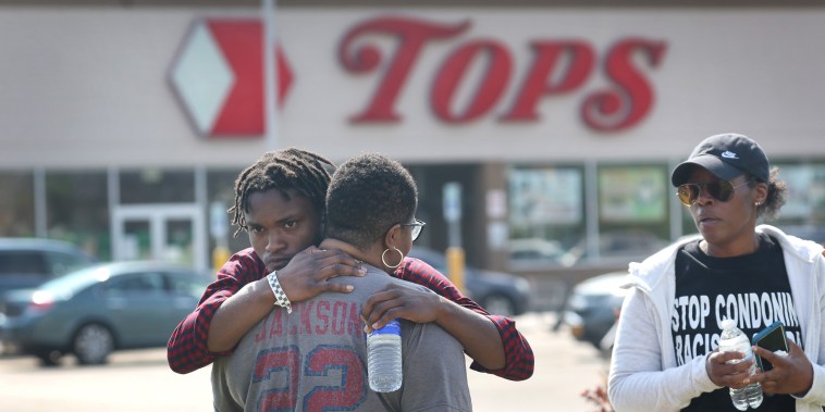 People embrace outside of the scene of a shooting at Tops Friendly Market