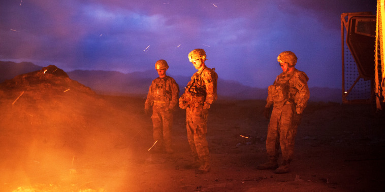 Soldiers burn trash in a burn pit