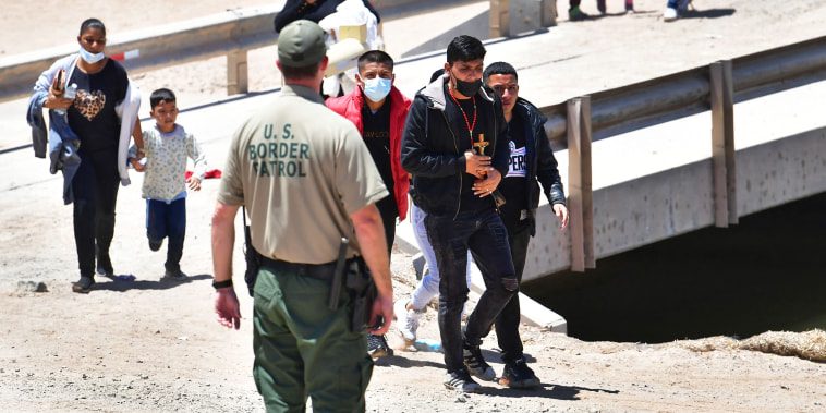 A U.S. Border Patrol officer directs migrants arriving at the border