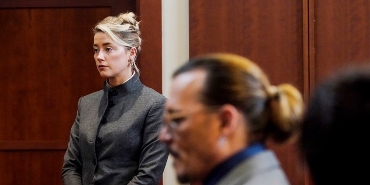 Amber Heard and Johnny Depp watch as the jury leave the courtroom for a lunch break at the Fairfax County Circuit Courthouse in Fairfax, Va., on May 16, 2022.