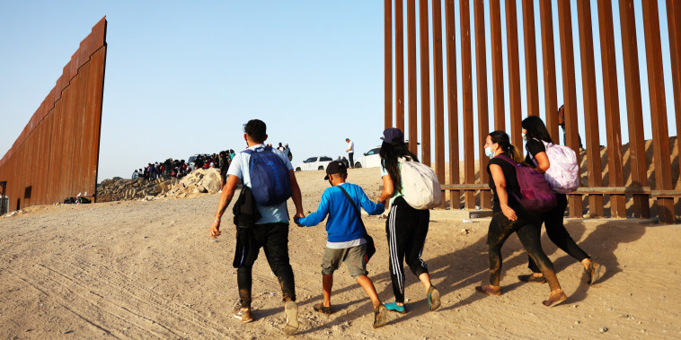 Immigrants cross through a gap in the U.S.-Mexico border