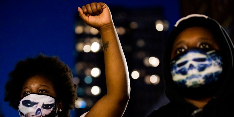 Image: A demonstrator raises a fist during a "Sit Out the Curfew" protest against the death of George Floyd 
along a street in Oakland, Calif., on June 3, 2020.