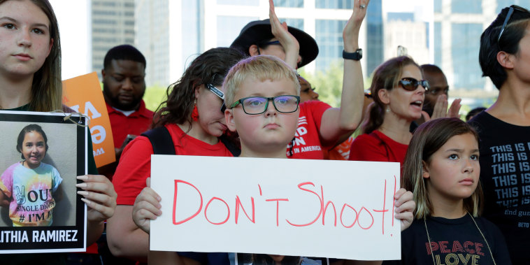 Unos niños sostienen pancartas y fotos de las víctimas del tiroteo en una escuela de Uvalde, Texas, durante una concentración en el parque Discovery Green, frente a la reunión anual de la Asociación Nacional del Rifle.