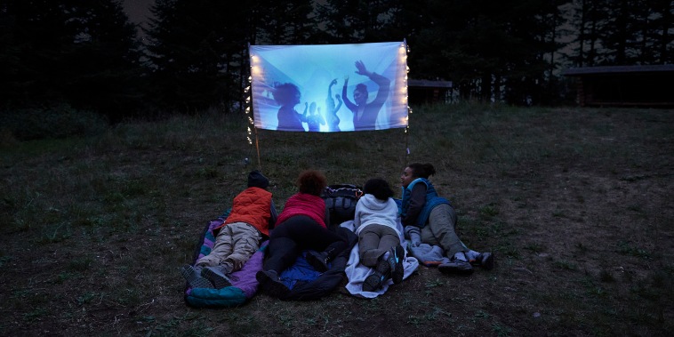 Friends watching video on screen at campsite