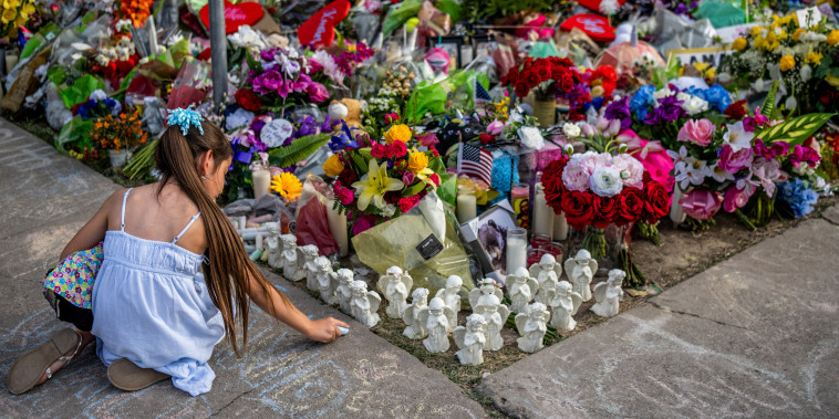 Lilly Garza pays her respects on May 31, 2022, with chalk at a memorial dedicated to the 19 children and two adults killed in the mass shooting at Robb Elementary School in Uvalde, Texas.