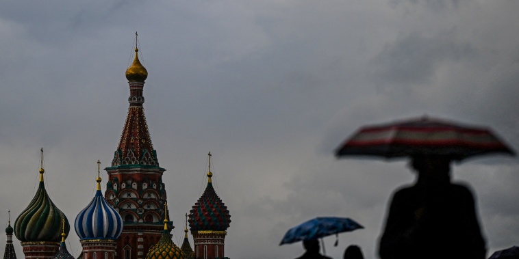 Image: People shelter from the rain under umbrellas while walking on Red Square in front of St. Basil's Cathedral in central Moscow on May 27, 2022.