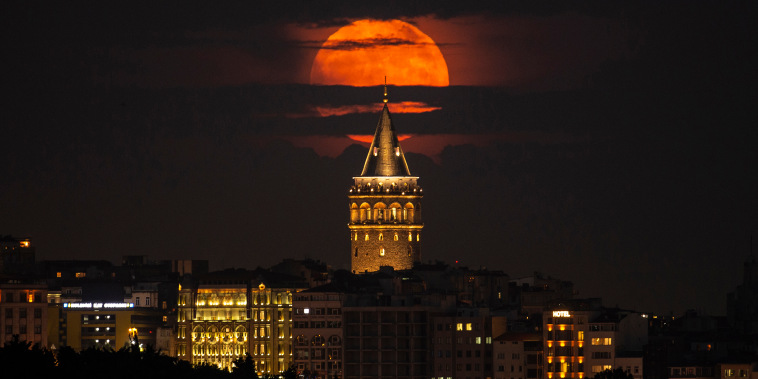 A supermoon rises behind the Galata Tower in Istanbul, Turkey, on June 14, 2022. The moon is a supermoon because of its proximity to Earth, and is also known as the "Strawberry Moon" because it is the full moon at strawberry harvest time.