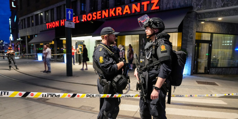Police stand guard outside a bar in central Oslo early Saturday after two people were killed and more than a dozen injured in a shooting.