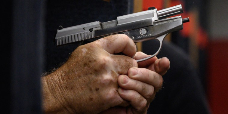 Shooting range owner John Deloca aims his pistol
