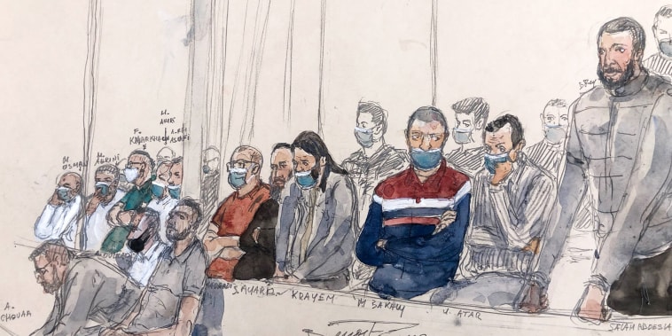 Salah Abdeslam, right, stands next to the 13 other defendants in front of Paris' special assize court during the trial of the November 2015 attacks that saw 130 people killed at the Stade de France in Saint-Denis, bars, restaurants and the Bataclan concert hall in Paris in this sketch made on June 27, 2022.