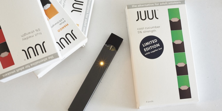 A Juul Labs Inc. e-cigarette and flavored pods are arranged for a photograph in the Brooklyn Borough of New York, U.S., on Sunday July 8, 2018. Juul Labs, the maker of the popular e-cigarette brand that has recently come under fire from health officials over its popularity with young adults, plans to introduce a line of lower-nicotine pods. The company will begin to sell pods with a 3-percent nicotine concentration in its mint and Virginia tobacco flavors later this year, according to a statement Thursday. Photographer: Gabby Jones/Bloomberg via Getty Images
