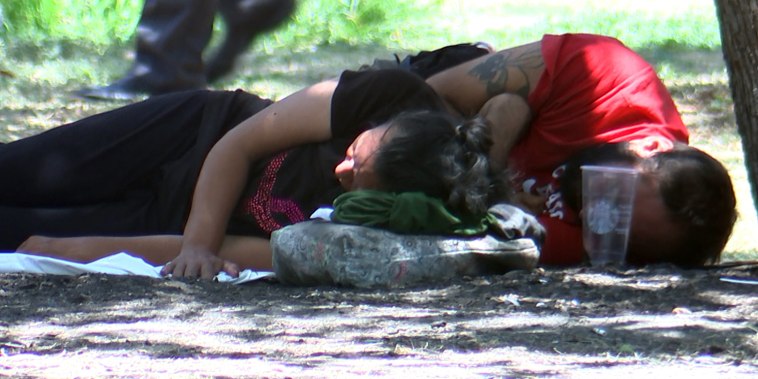 Migrants rest at a park during a hot day in July, in San Antonio.
