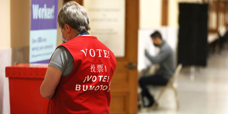 A poll worker wears a vest adorned with the word "vote"