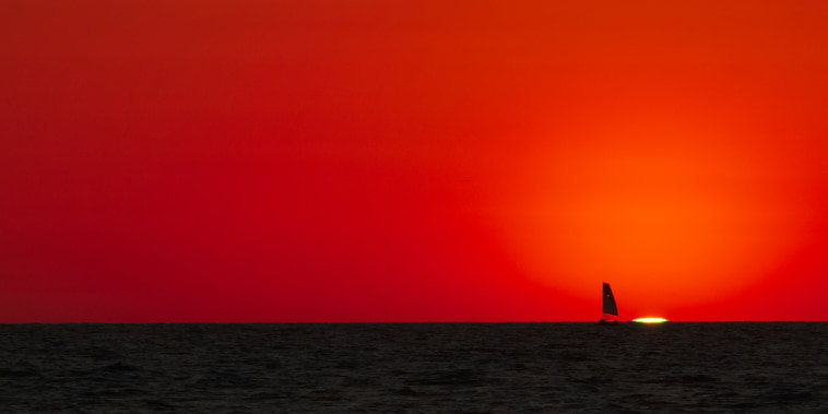 A sail boat passes the setting sun in Fort Myers Beach, Fla., Mar. 2, 2014.