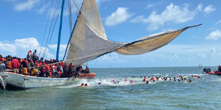 Migrantes haitianos saltan al agua luego de que la Guardia Costera hallara su embarcación encayada en Key Largo, Florida, el 6 de agosto de 2022.