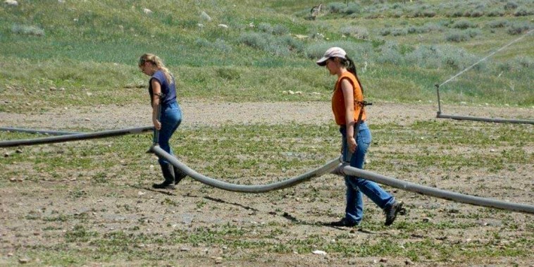 Image: Clarice Steg, left, and Maggie Higgins carry irrigation pipes at the ranch. Trinity Teen Solutions sent Higgins’ parents this photo as part of an update on her time at the ranch.