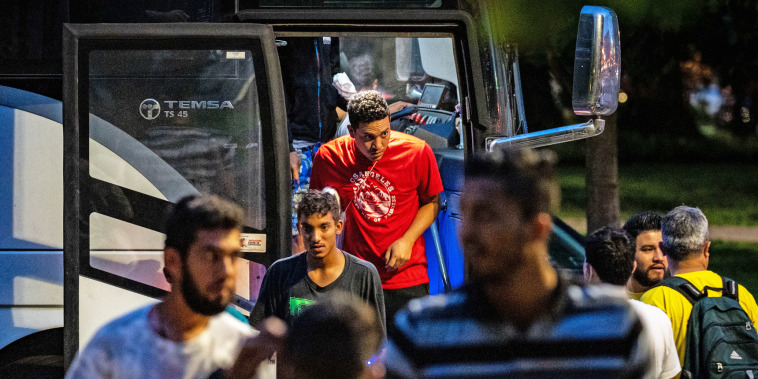 Migrants disembark a bus from Texas within view of the Capitol