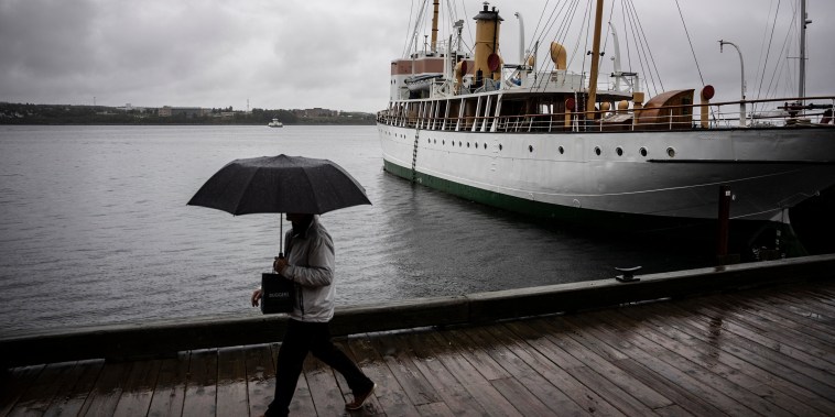 Image: A pedestrian shields themselves with an umbrella while walking along the Halifax waterfront as rain falls ahead of Hurricane Fiona making landfall in Halifax, on Sept. 23, 2022.