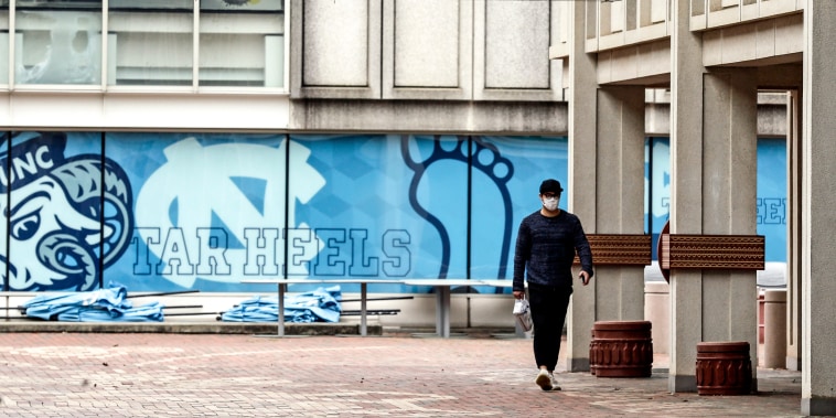 A pedestrian walks through campus at the University of North Carolina in Chapel Hill, N.C., on March 18, 2020.