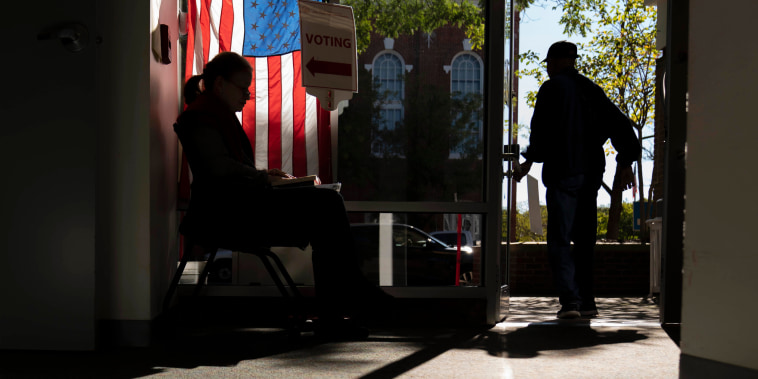 A poll worker greets early voters in Alexandria, Va., on Sept. 26, 2022.