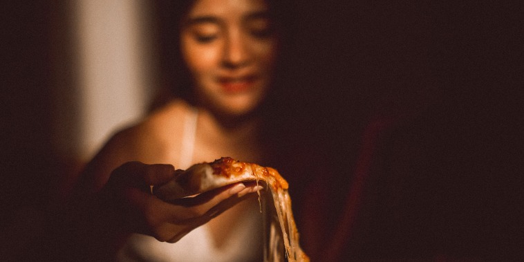 Close-Up Of Woman Eating Pizza At Home
