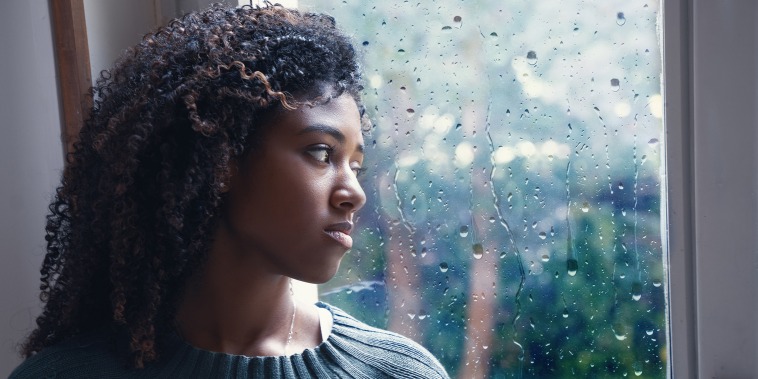 Young worried woman looking out of the window
