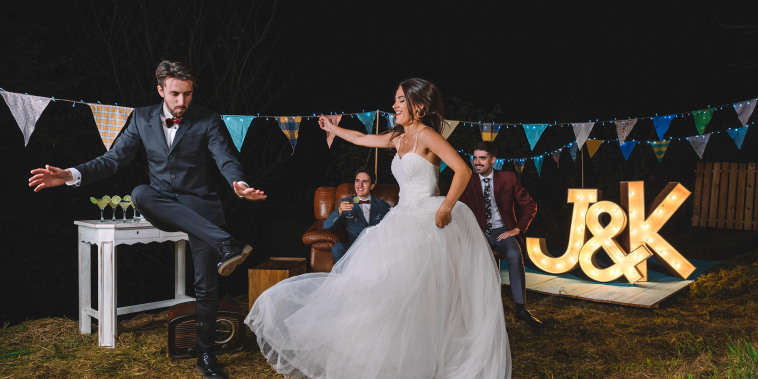 Happy bride and man dancing on a night field party
