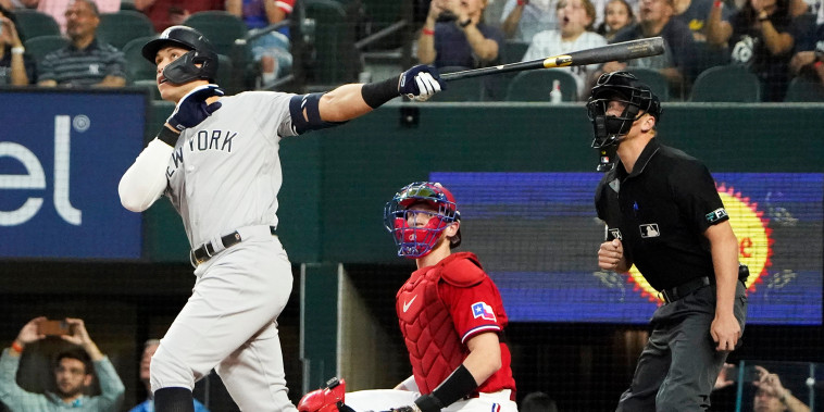 New York Yankees' Aaron Judge, left, hits a solo home, his 62nd of the season, in front of Texas Rangers catcher Sam Huff and home plate umpire Chris Segal during the first inning in the second baseball game of a doubleheader in Arlington, Texas, Tuesday, Oct. 4, 2022.