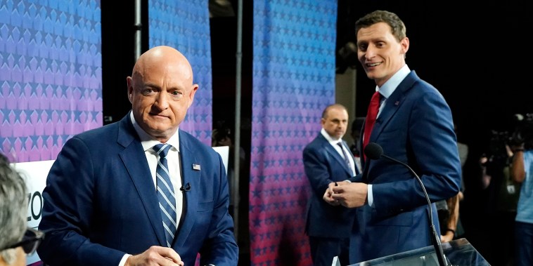 Arizona Democratic Sen. Mark Kelly, left, Republican challenger Blake Masters, right, and Libertarian Marc Victor, back, pause on the stage prior to a televised debate in Phoenix, Thursday, Oct. 6, 2022.
